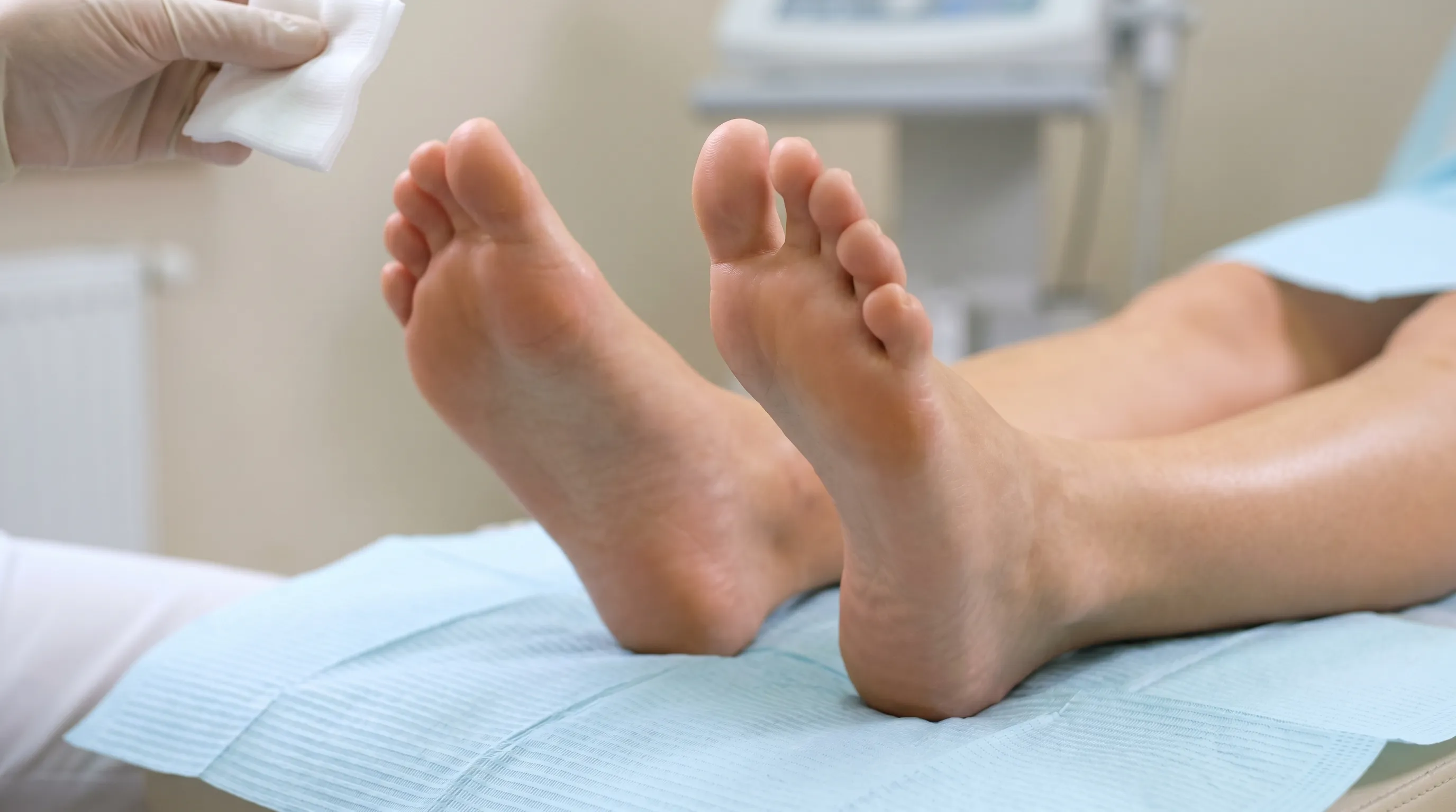 A close-up clinical photograph showing healthy foot soles with natural skin variation, soft lighting, and a clean medical wellness background